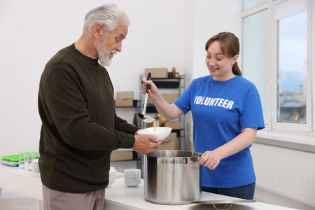 Humanitarian aid for elderly people. Volunteer giving meal to senior man indoorsの写真素材