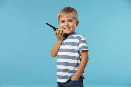 Little boy with walkie talkie toy on light blue backgroundの写真素材