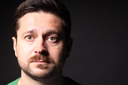 Sad man crying on black background, space for textの写真素材