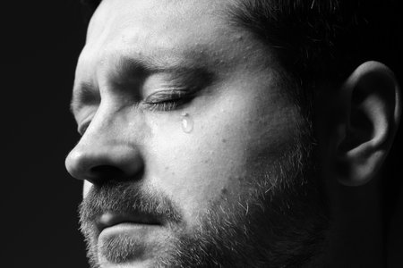 Sad man crying on dark background, closeup. Black and white effectの写真素材