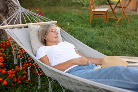 Senior woman resting in comfortable hammock outdoorsの写真素材