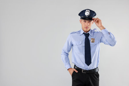 Young policeman in uniform on light gray background, space for textの写真素材