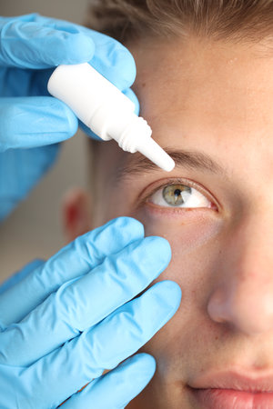 Doctor putting drops into man's eye indoors, closeupの写真素材