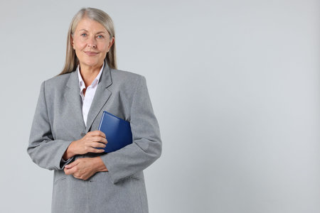 Portrait of professional psychotherapist with notebook on light gray background, space for text