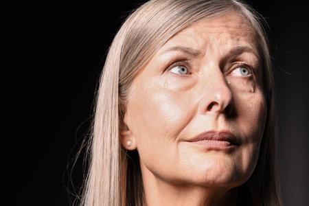Senior woman crying on black background, closeup. Space for textの写真素材