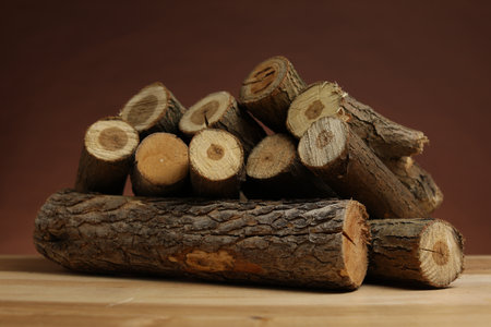 Pile of cut firewood on wooden table against brown backgroundの写真素材