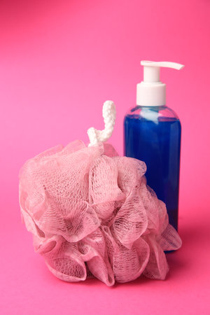 Shower puff and bottle of cosmetic product on pink backgroundの写真素材