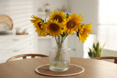 Beautiful sunflowers in vase on wooden table at homeの写真素材