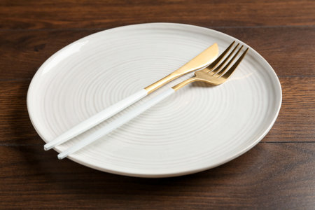 Clean ceramic plate and cutlery on wooden table, closeupの写真素材