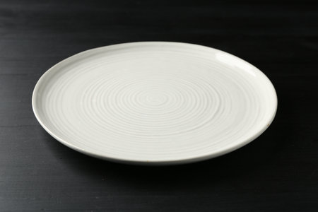 Empty ceramic plate on black wooden table, closeupの写真素材