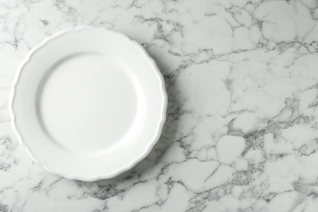 Stylish ceramic plate on white marble table, top view. Space for textの写真素材