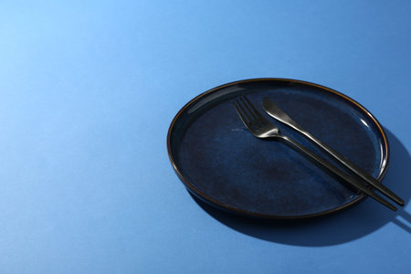 Ceramic plate and cutlery on blue background. Space for textの写真素材