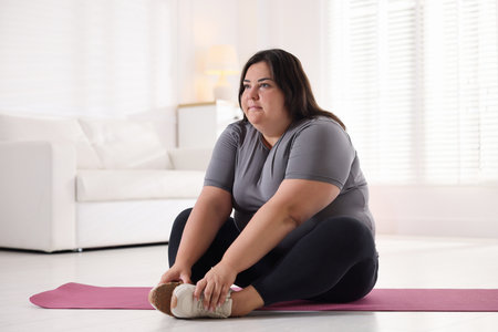 Woman in sportswear training on yoga mat at homeの写真素材