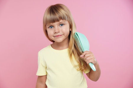 Little girl brushing her hair on pink backgroundの写真素材