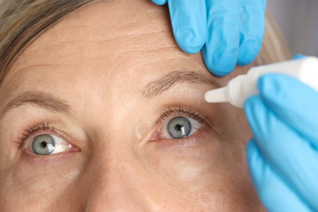 Doctor putting drops into woman's eye indoors, closeup