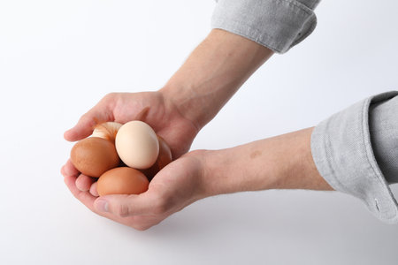 Man with raw chicken eggs on white background, closeupの写真素材