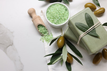 Natural soap bars, olives and sea salt on white marble table, flat lay. Space for textの写真素材