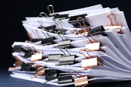Many documents with binder clips on dark background, closeupの写真素材