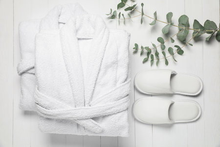 Flat lay composition with bathrobes, slippers and eucalyptus on white wooden background. Spa and relaxの写真素材
