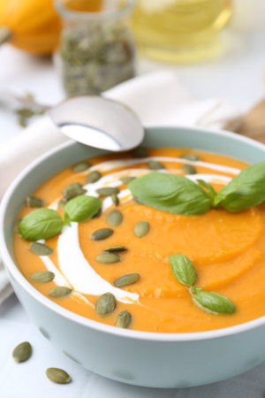 Delicious pumpkin soup with seeds and basil in bowl on table, closeupの写真素材