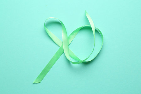 Beautiful light green ribbon on turquoise background, top viewの写真素材