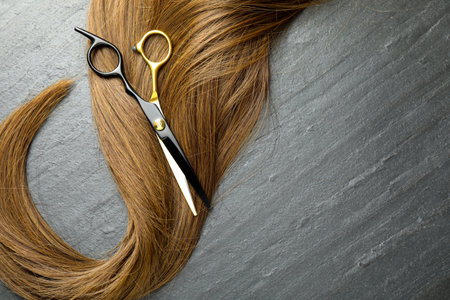 Beautiful hair strands and scissors on gray background, top view. Space for textの写真素材