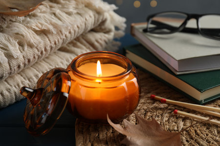 Autumn composition with burning candle on blue wooden table against blurred lights, closeupの写真素材