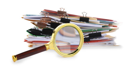 Stack of colorful folders with documents, binder clips and magnifying glass isolated on whiteの写真素材