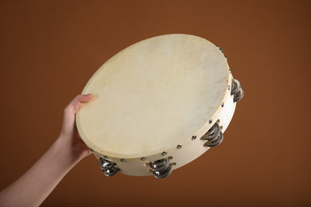 Woman playing tambourine on brown background, closeupの写真素材