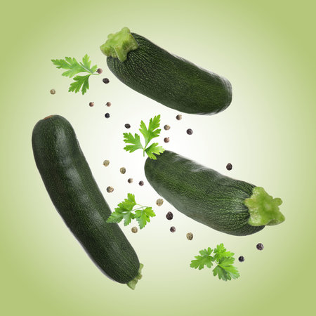 Fresh zucchini and parsley falling against light green backgroundの写真素材