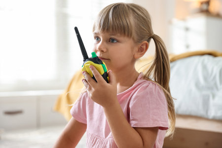 Little girl playing with walkie talkie toy at homeの写真素材
