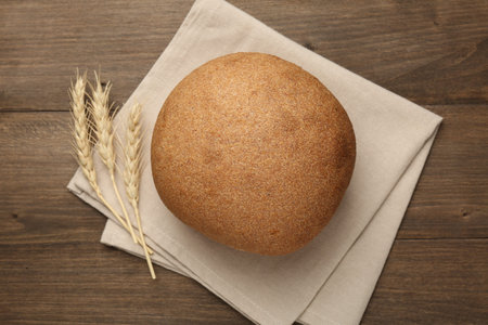 Loaf of fresh bread on wooden table, flat lay
