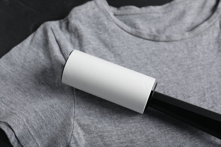 Lint roller and gray t-shirt on black table, closeupの写真素材