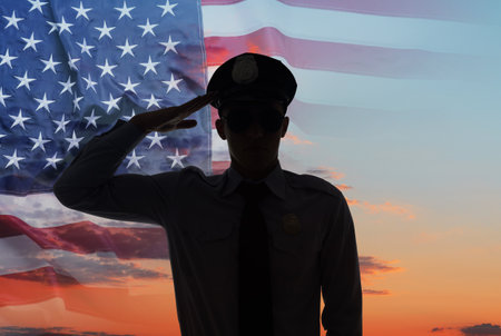 Police force. Man in uniform saluting against sky, double exposure with flag of USAの写真素材