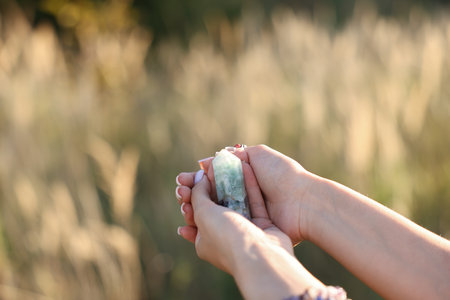 Woman meditating with crystal to heal or restore her aura outdoors, closeup. Space for textの写真素材