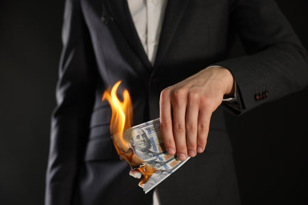 Man burning dollar banknotes on black background, closeupの写真素材