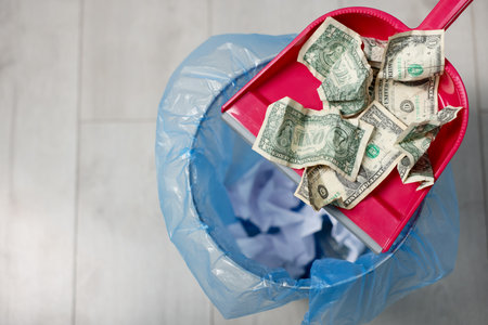 Dollar banknotes, dustpan and trash bin on floor, top view. Space for textの写真素材