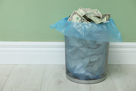 Dollar banknotes in trash bin indoors. Space for textの写真素材