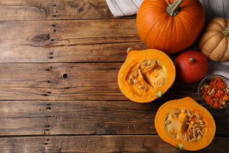 Fresh pumpkins and seeds on wooden table, flat lay. Space for textの写真素材