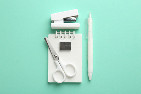 Stapler and other stationery on turquoise background, flat layの写真素材