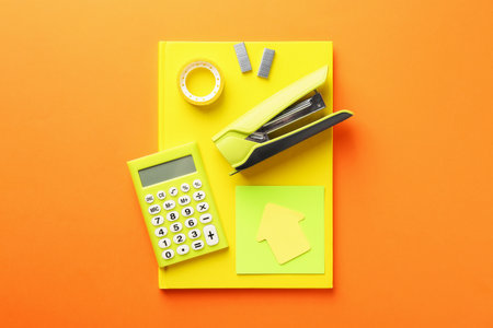 Stapler and other stationery on orange background, top viewの写真素材