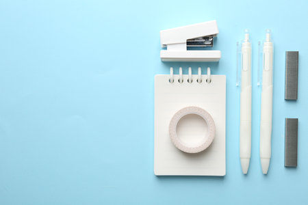 Stapler and other stationery on light blue background, flat lay. Space for textの写真素材