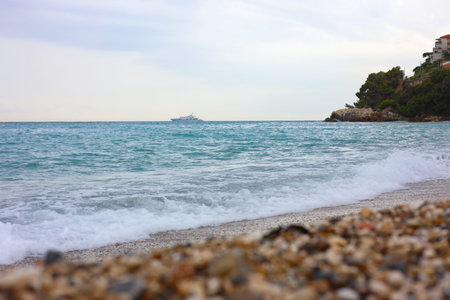 Beautiful view of wavy sea and pebbles on beach, selective focus