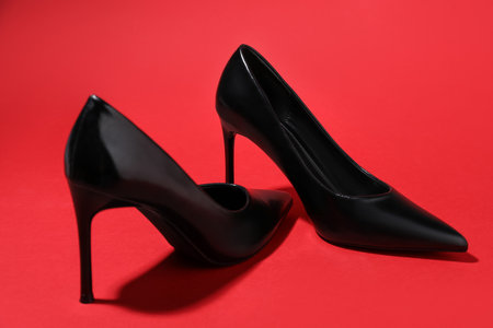 Pair of stylish high heeled shoes on red background, closeupの写真素材