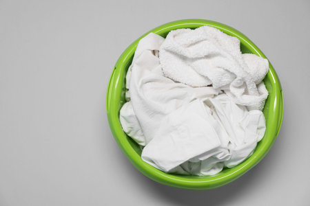 Plastic basin with clothes on light gray background, top view. Space for textの写真素材
