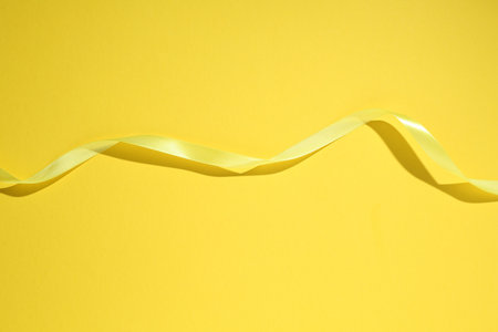 Beautiful ribbon on yellow background, top viewの写真素材