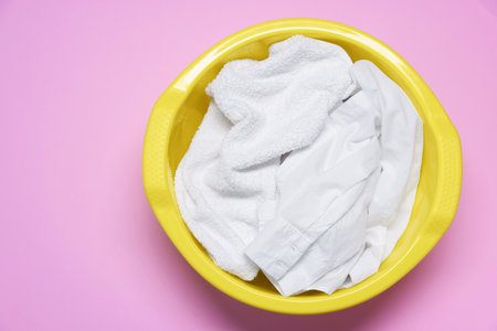Plastic basin with clothes on pink background, top viewの写真素材