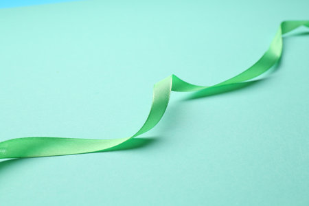 Beautiful light green ribbon on turquoise background, closeupの写真素材