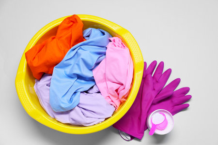 Plastic basin with clothes, gloves and washing powder on light gray background, flat layの写真素材