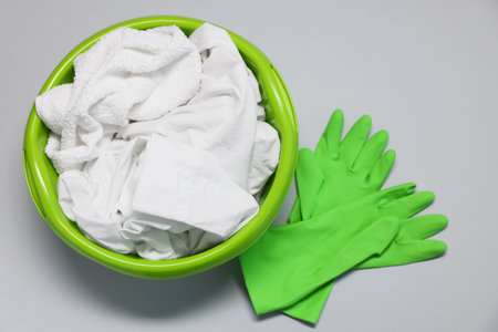 Plastic basin with clothes and gloves on light gray background, top viewの写真素材